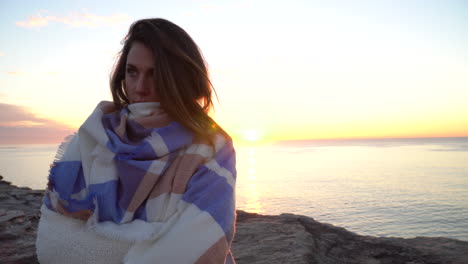 young brunette girl hiking in nature standing at sunrise on ocean cliff with subtle lens flare