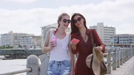 two young woman talking selfie together on summer vacation beach seaside promenade