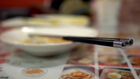 un plato vacío después de comer comida en un restaurante. con palillos. el fondo borroso es una niña comiendo.