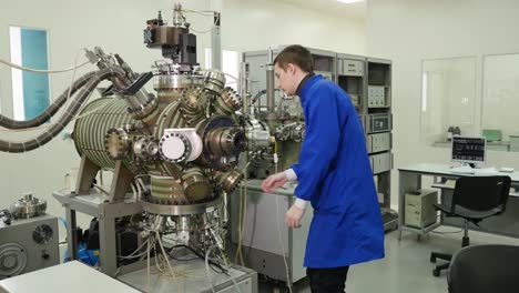 scientist working with a large vacuum chamber in a laboratory