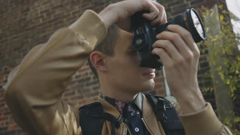 young man photographer taking photo with his camera while standing outdoors during daylight