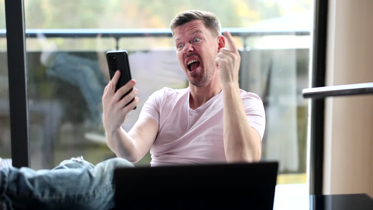 Man on a video call using a smartphone and laptop
