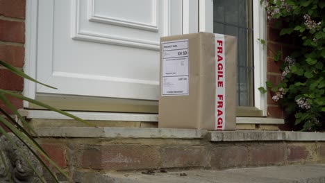 Male-Courier-Placing-Parcel-On-Doorstep