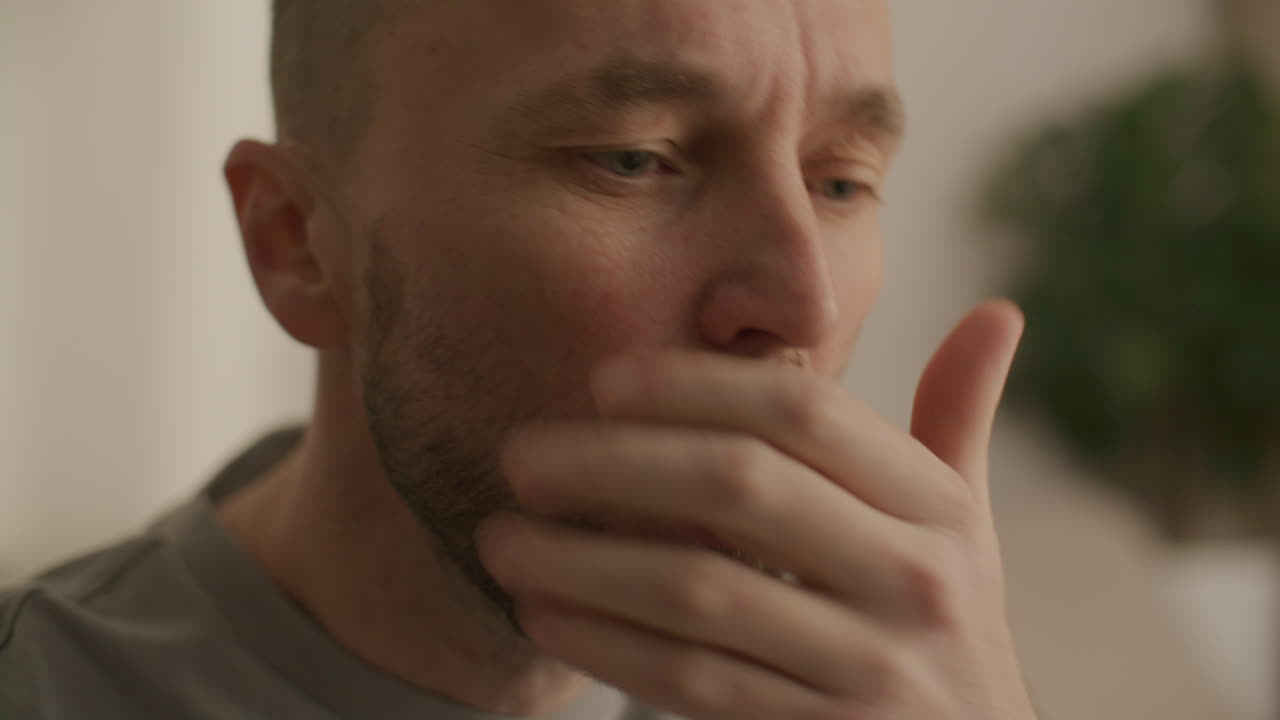 Close-up of Man Coughing and Covering Mouth with Hand