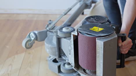 technician flips heavy floor sanding machine on its side for maintenance and inspection
