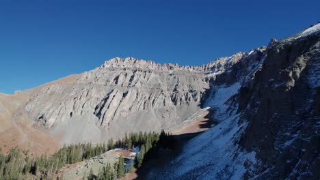 Drone-shot-turning-around-the-corner-to-reveal-steep-mountain-peaks