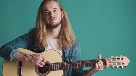 caucasian young man playing guitar on camera.