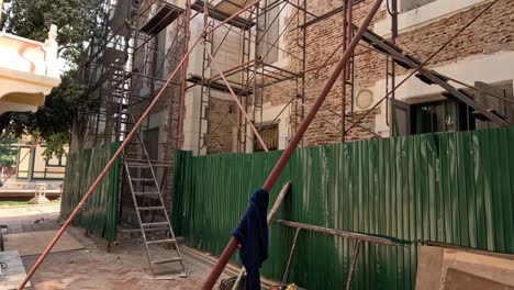 trabajador trepando el andamio para instalar sábanas onduladas verdes