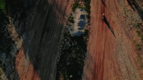 arriba hacia abajo siguiendo a un jinete de bicicleta de tierra que sale de las vías de la carretera seguido de un atv