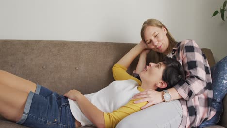 caucasian woman lying on the lap of her wife on the couch at home