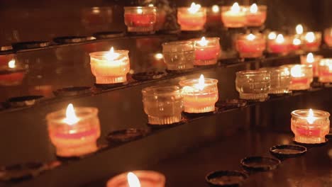 rows of lit candles in a church