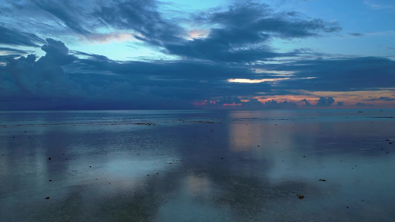 Calm ocean water reflecting a dramatic cloudy sky during a peaceful sunset creating a serene atmospheric landscape. Unbelievable aerial view fly reverse drone panorama