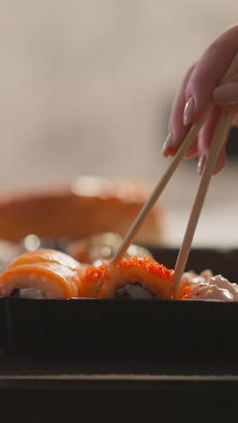 woman hand takes delicious sushi roll with chopsticks in restaurant closeup. lady enjoys asian food for dinner slow motion. luxury lifestyle