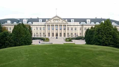 the exterior of a large building with a lawn and flag