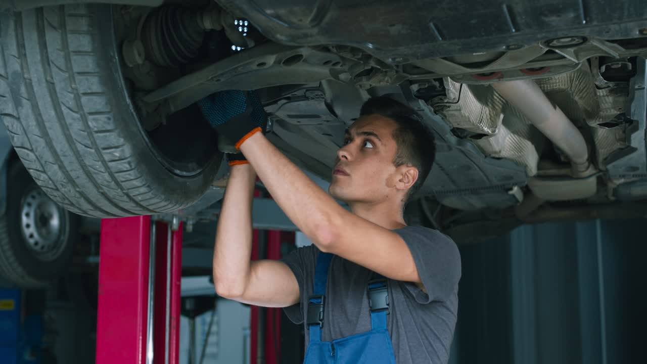 mecánico de automóviles que trabaja en el tren de aterrizaje de un vehículo