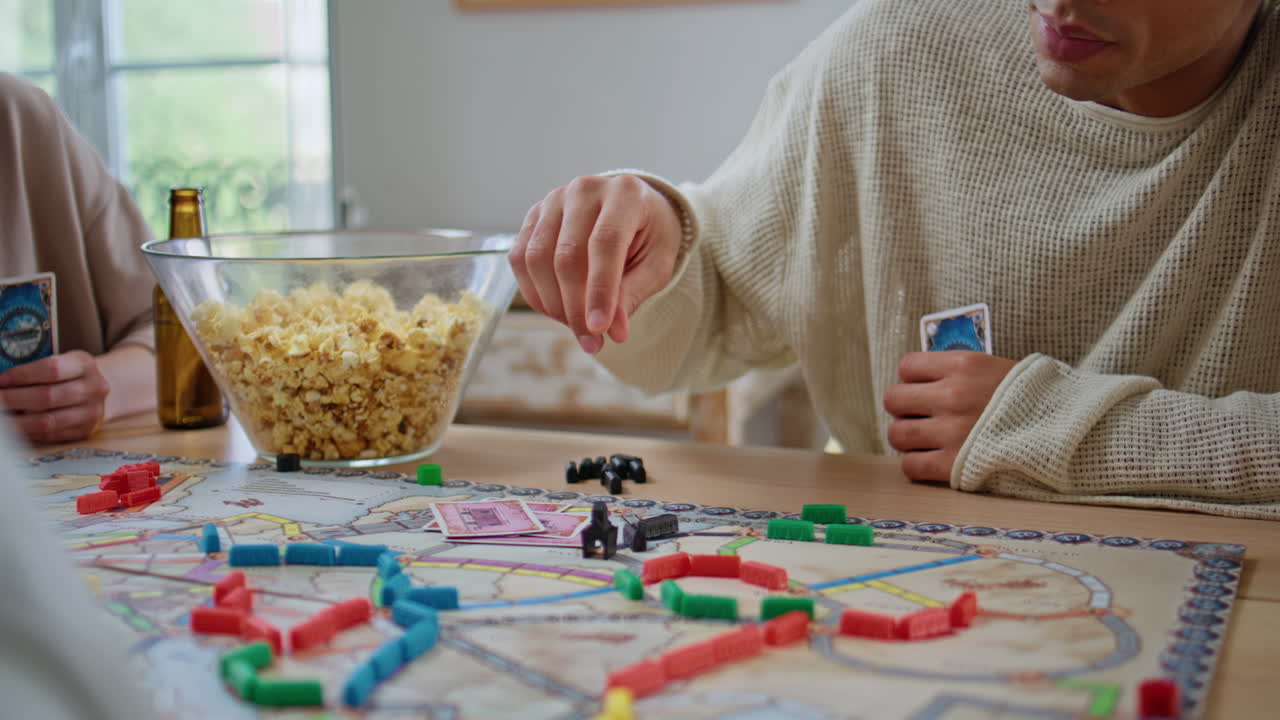 Woman player holding cards playing game at apartment closeup. Board games party