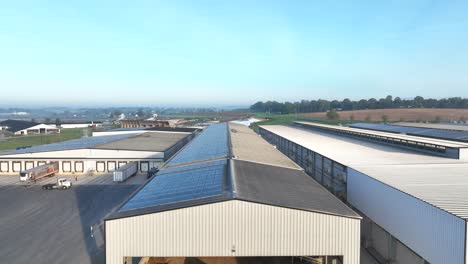 industrial chicken farm with large white sheds, a gravel mound, and a spacious paved area for operations, set against a clear sky