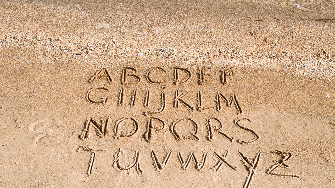 English alphabet written on a beach sand. Shooting on the beach