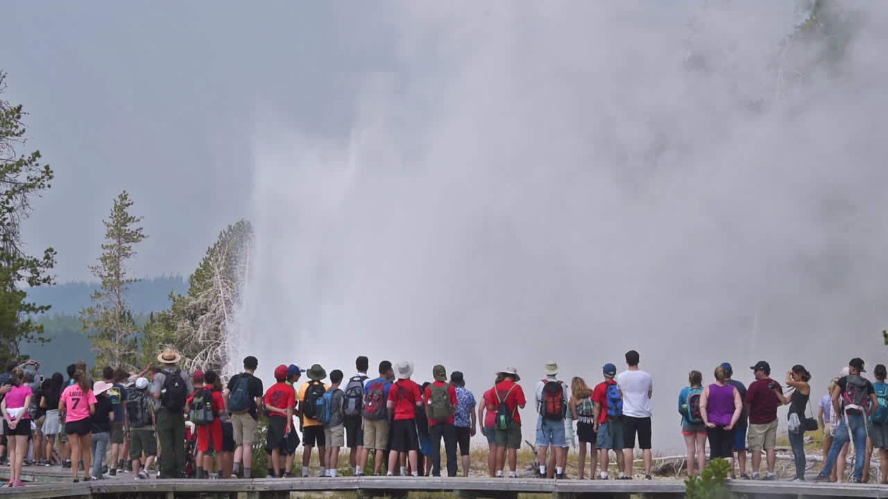 많은 관광객들이 옐로스톤 국립공원에서 오래된 충실한 간헐천의 분출을 관찰합니다.