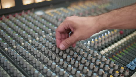 hand adjusting channels on mixing console