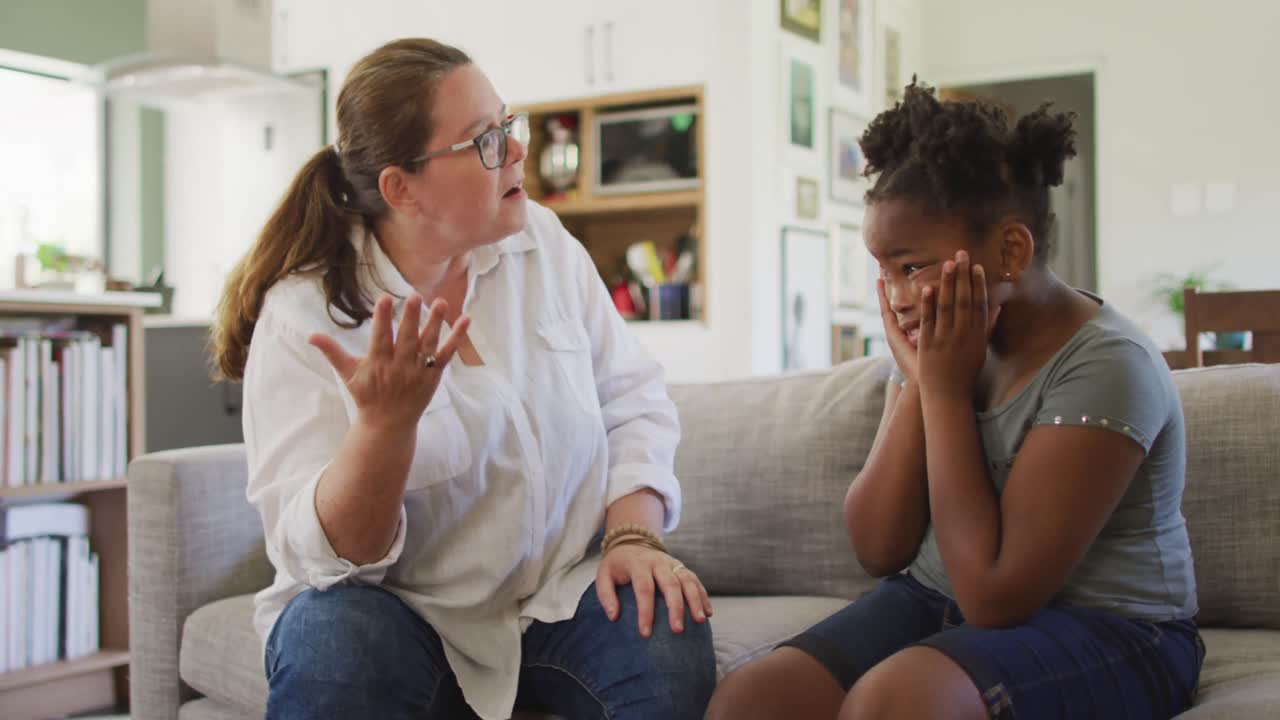 Donna caucasica che discute con la figlia afroamericana in soggiorno.