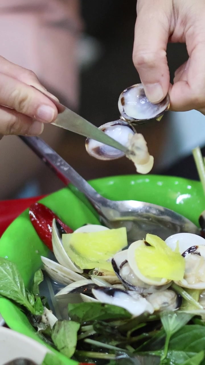 Hands removing clam shells over a fresh salad