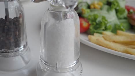 table with salt and pepper shakers, salad, fries, and other food
