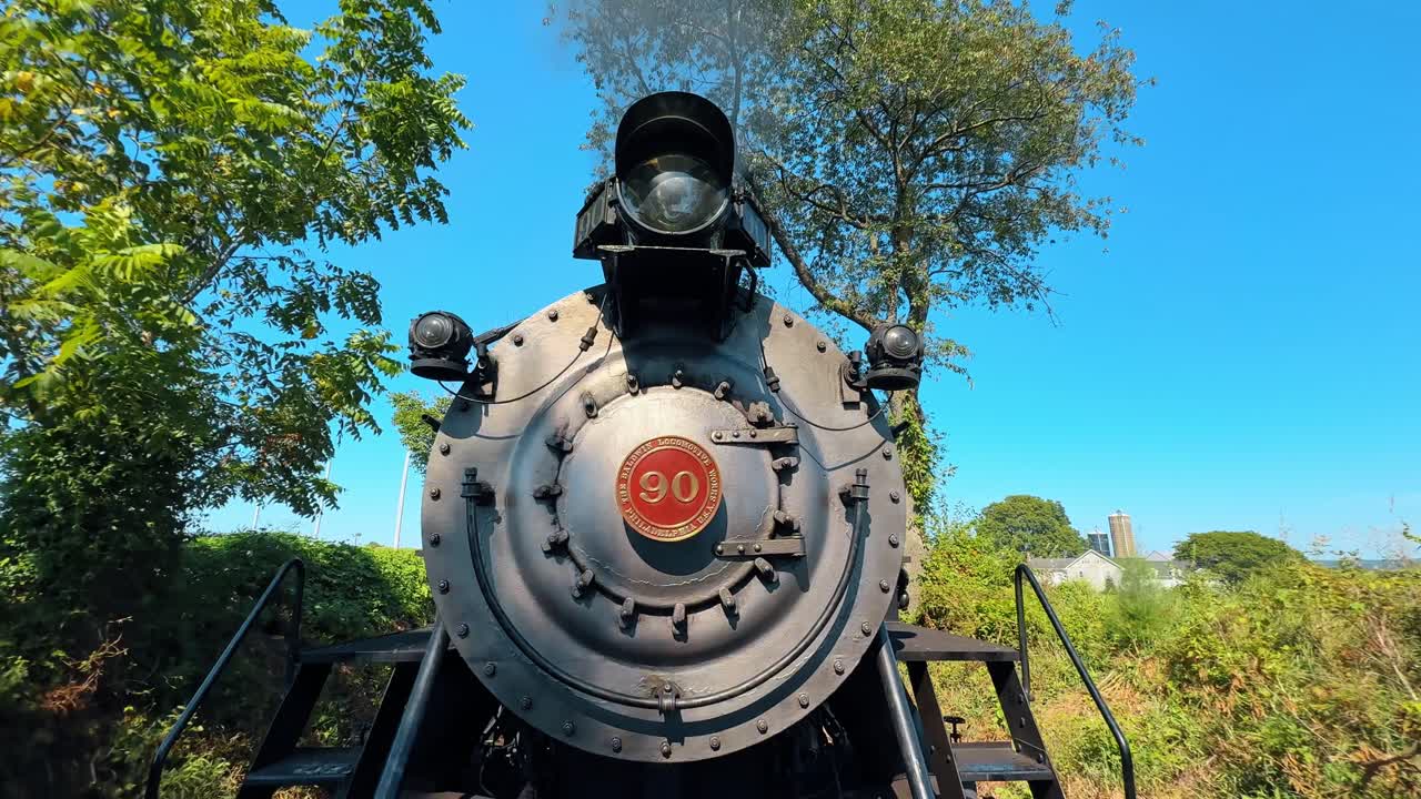 Boston, EUA, 8 de maio de 2025: Vista frontal da locomotiva a vapor vintage Baldwin número 90. Close-up da frente de uma máquina a vapor cinza com placa numérica vermelha contra céu azul claro