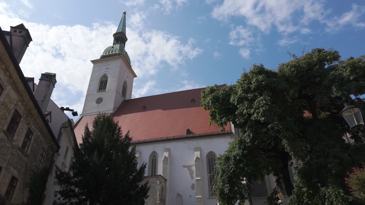 St. Martin's Cathedral in Bratislava, featuring its iconic tower against a bright sky with surrounding buildings