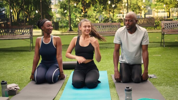 Woman instructor in seated forward fold pose with knees at chest on yoga mat