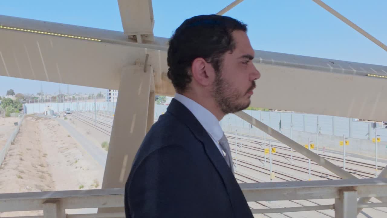 Empresario en traje formal mirando las vías del tren desde un puente