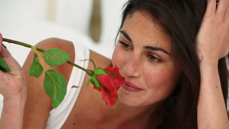 una mujer oliendo una rosa roja.
