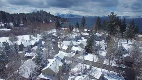 Una-Antena-Sobre-Un-Pueblo-Cubierto-De-Nieve-En-Las-Montañas-De-Sierra-Nevada-Con-El-Lago-Tahoe-Ion-El-Fondo-1