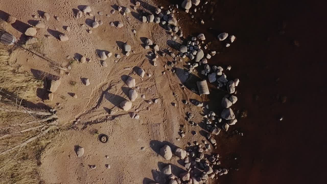 orilla rocosa de la playa con muchos cantos rodados y naturaleza nórdica azul del mar, árboles desnudos, vista aérea desde arriba