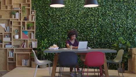 young black business woman using laptop computer working late sending email brainstorming project in trendy startup office