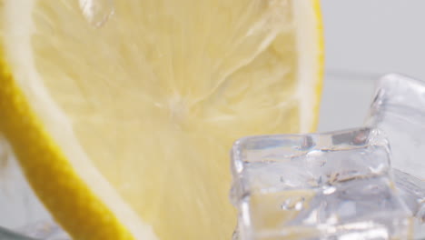 Cold-fresh-sparkling-water-pouring-into-a-glass-with-ice-and-lemon-slices