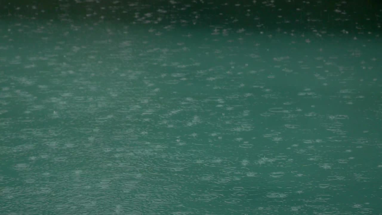 la lluvia tropical de verano salpicando en la piscina. cerca de la piscina durante la tormenta y las gotas de lluvia cayendo en el agua.
