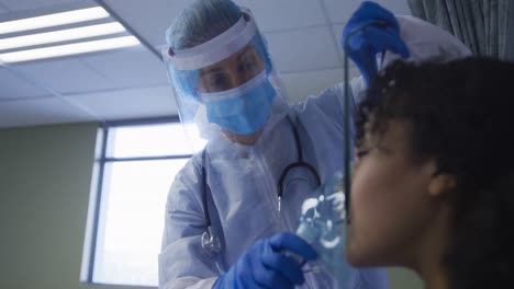 doctora caucásica poniendo una máscara de oxígeno en una mujer afroamericana en el hospital