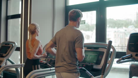 Fit-couple-running-on-treadmill-at-gym.-Sporty-family-doing-cardio-in-sport-club