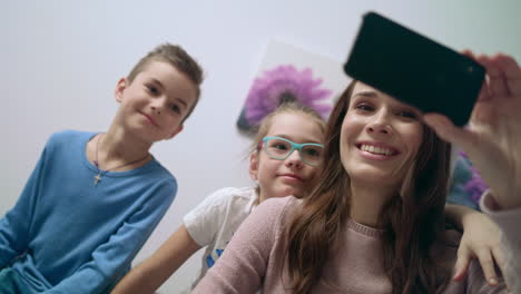mujer sonriente tomando selfies con niños