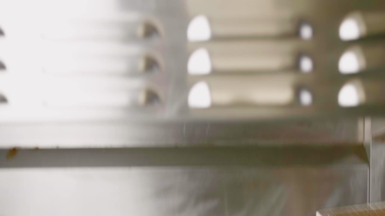 Potato wedges are poured onto grate in fast food kitchen, tilt down