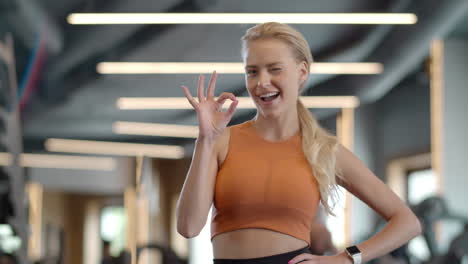 cheerful athlete girl showing ok sign at gym. sportswoman standing in sport club