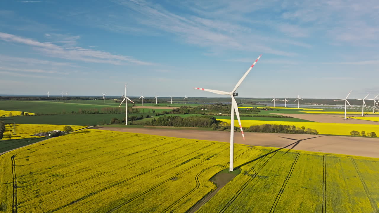 Wind Turbines Spinning Over The Canola Rapeseed Fields. - aerial shot