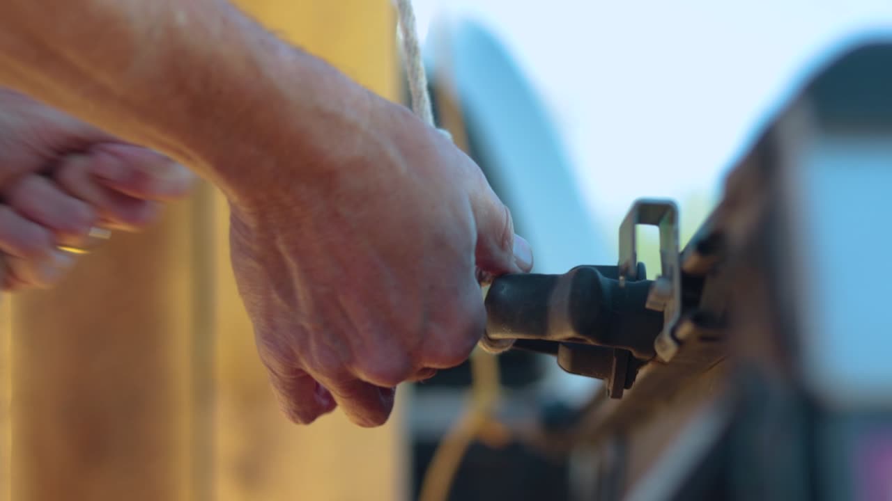 Old white man's hands securing a load in the back of the truck tying a double knot on the truck.