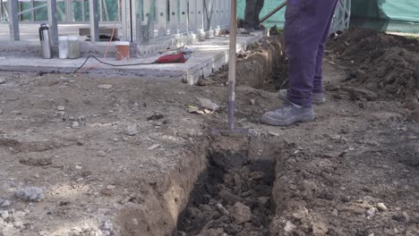 primer plano de un hombre de trabajo cavando un hoyo con una pala en el sitio de construcción - toma de pista de 4k
