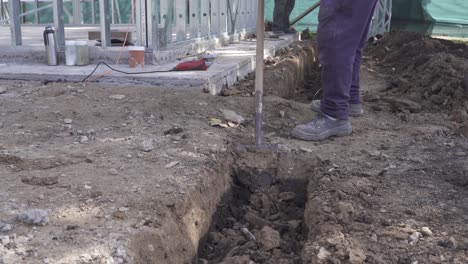 close up shot of labor man digging hole with shovel on construction site - 4k track shot