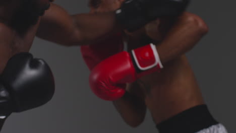 toma de estudio de cerca de dos boxeadores masculinos con guantes luchando en un partido de boxeo contra un fondo gris 16