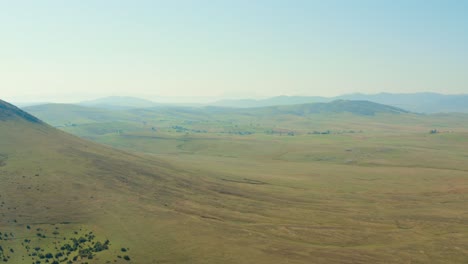 aerial shot over a vast open plain with hills in the distance