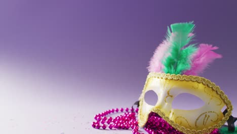 video of carnival masquerade mask with feathers and pink mardi gras beads, with copy space