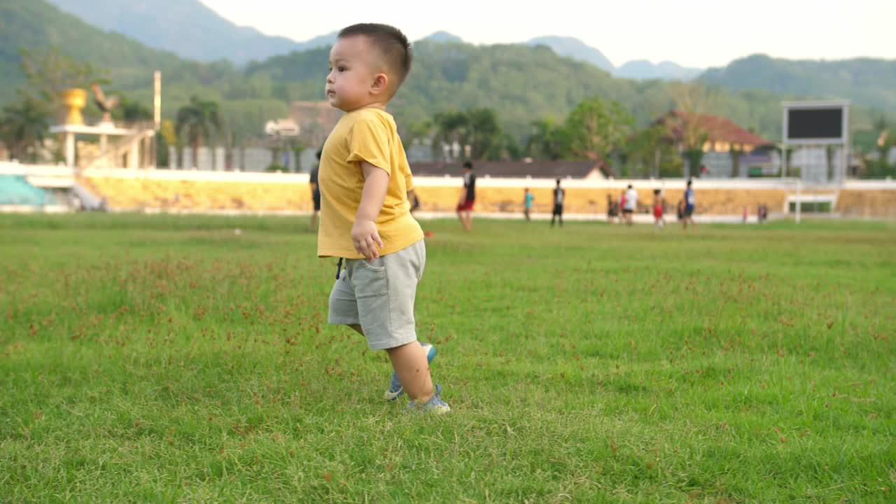 Balita laki-laki Asia yang lucu di rumput stadion